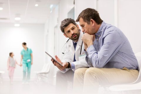 doctor,discussing,over,digital,tablet,with,mature,patient,at,hospital