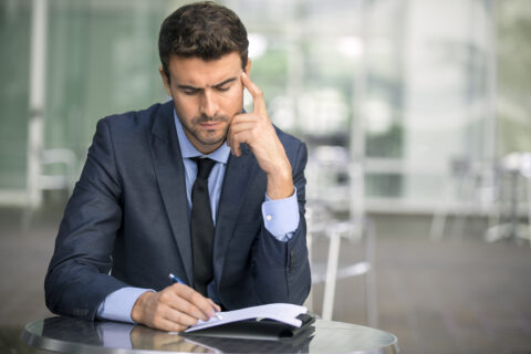 focused,businessman,thinking,and,writing,outside,office,into,report,file